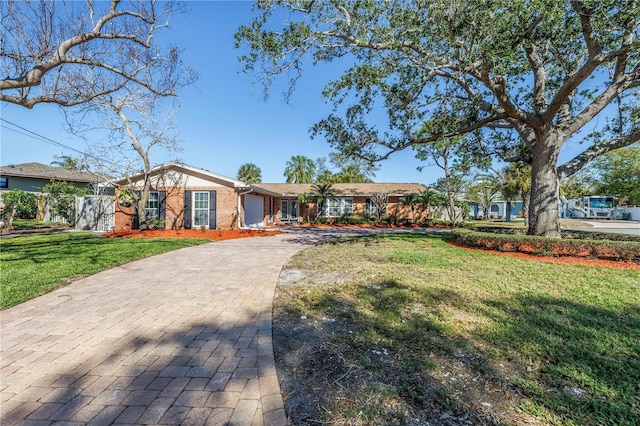 ranch-style house with a front yard, decorative driveway, and brick siding