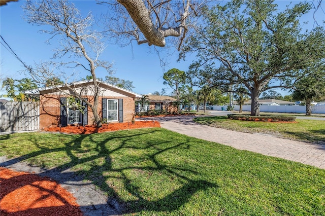 view of front of property with a front lawn, fence, and brick siding