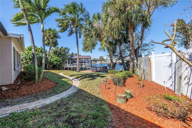 view of yard with boat lift, a dock, and fence