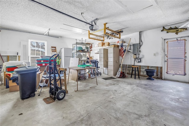 garage with electric panel, a garage door opener, and freestanding refrigerator