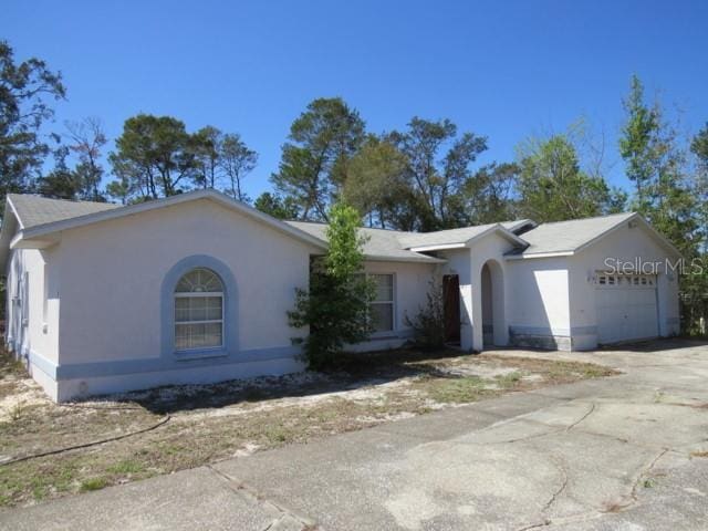 ranch-style home with a garage, driveway, and stucco siding