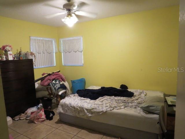 tiled bedroom featuring ceiling fan