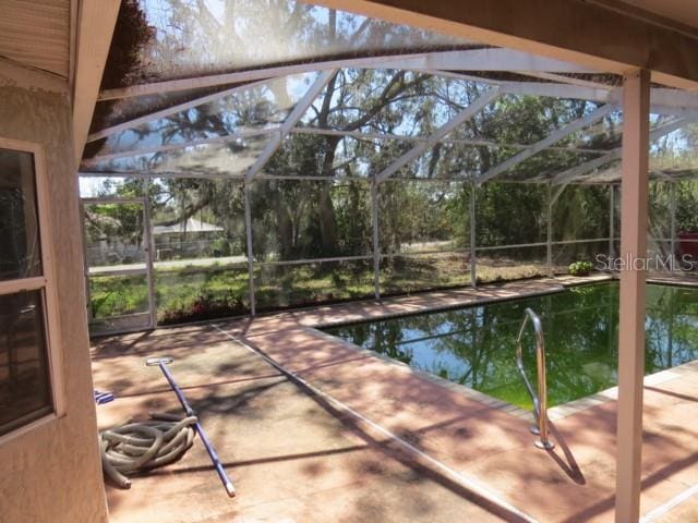 pool with glass enclosure and a patio