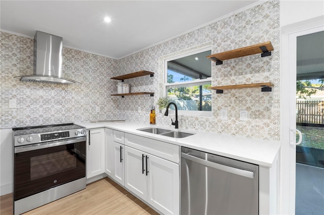 kitchen featuring ornamental molding, open shelves, a sink, appliances with stainless steel finishes, and wall chimney range hood