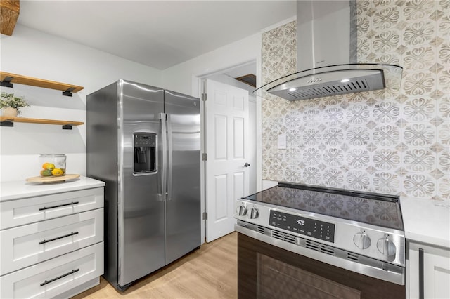 kitchen featuring stainless steel appliances, light wood-style flooring, light countertops, and wall chimney range hood