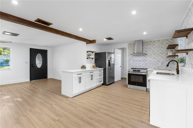 kitchen featuring light wood-type flooring, open shelves, a sink, stainless steel appliances, and wall chimney exhaust hood