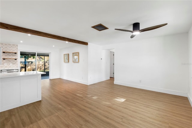 unfurnished living room with light wood finished floors, beamed ceiling, ceiling fan, and baseboards