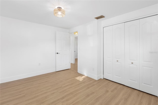 unfurnished bedroom with light wood-style flooring, visible vents, baseboards, and a closet