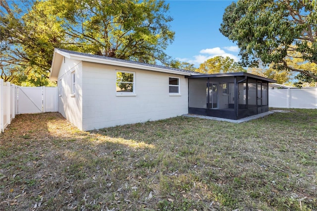 rear view of property with a gate, a yard, a fenced backyard, and a sunroom