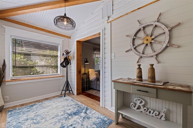 interior space with wooden walls, visible vents, baseboards, lofted ceiling, and wood finished floors