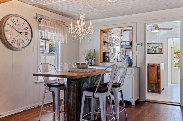 dining space with a notable chandelier, dark wood-type flooring, wood ceiling, and crown molding