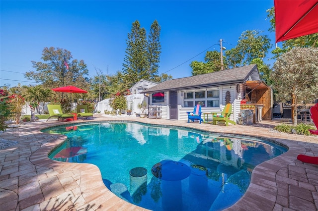 view of swimming pool with an outbuilding, a patio, fence, a fenced in pool, and a storage structure