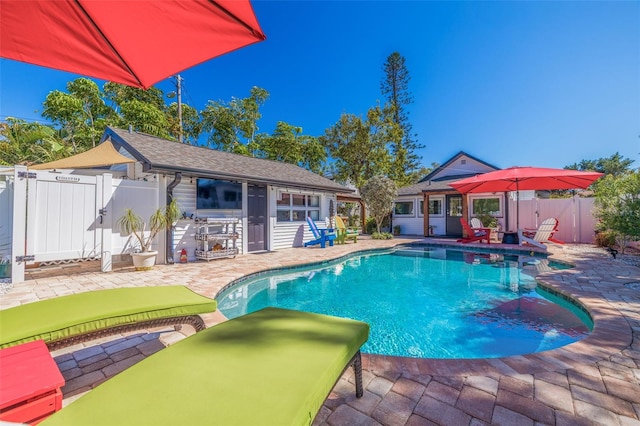 view of swimming pool featuring a patio, fence, a fenced in pool, an outdoor structure, and a storage structure