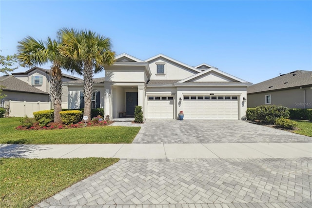 view of front of property with a front lawn, a garage, decorative driveway, stucco siding, and fence