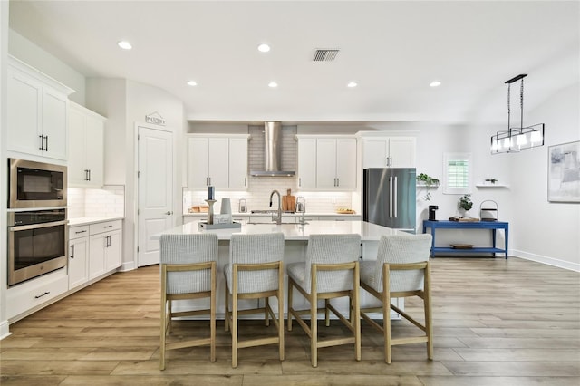 8766 Shadyside Ln, Land O Lakes, FL 34637 - kitchen with appliances with stainless steel finishes, wall chimney exhaust hood, light countertops, tasteful backsplash, and an island with sink
