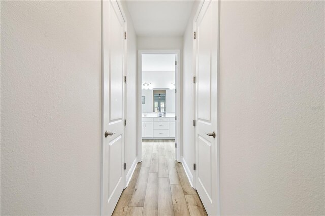 8766 Shadyside Ln, Land O Lakes, FL 34637 - corridor with light wood-style flooring, a textured wall, and baseboards