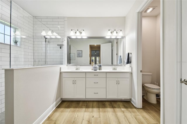8766 Shadyside Ln, Land O Lakes, FL 34637 - bathroom featuring double vanity, wood finished floors, walk in shower, toilet, and plenty of natural light