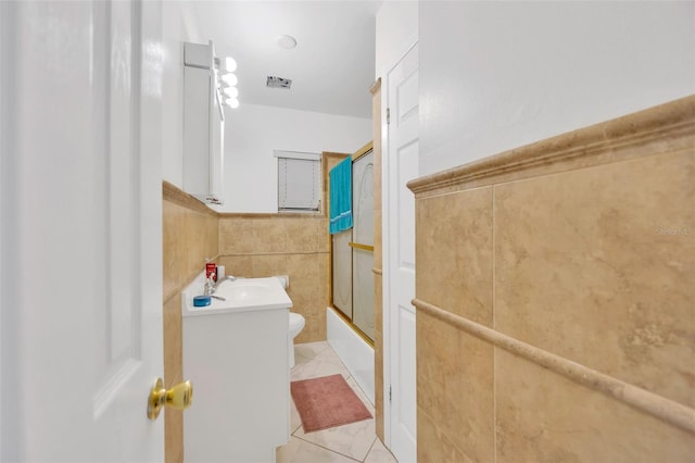 full bathroom featuring tile walls, toilet, shower / bath combination with glass door, tile patterned floors, and vanity