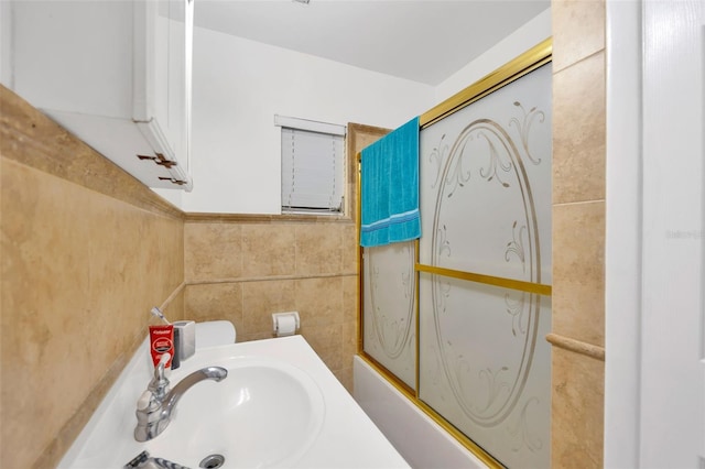 full bath with a sink, tile walls, and washtub / shower combination