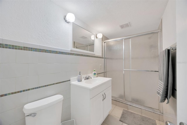 bathroom featuring visible vents, a textured ceiling, a stall shower, and vanity