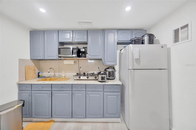 kitchen with visible vents, gray cabinetry, freestanding refrigerator, and a sink