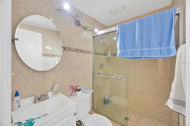 bathroom with vanity, visible vents, a stall shower, tile walls, and toilet