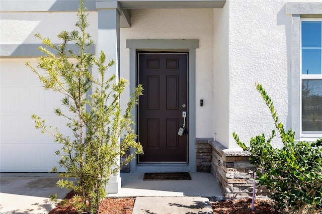 doorway to property featuring stucco siding and a garage