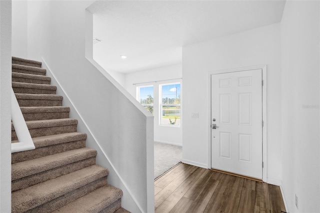 entryway with dark wood-type flooring, stairway, and baseboards