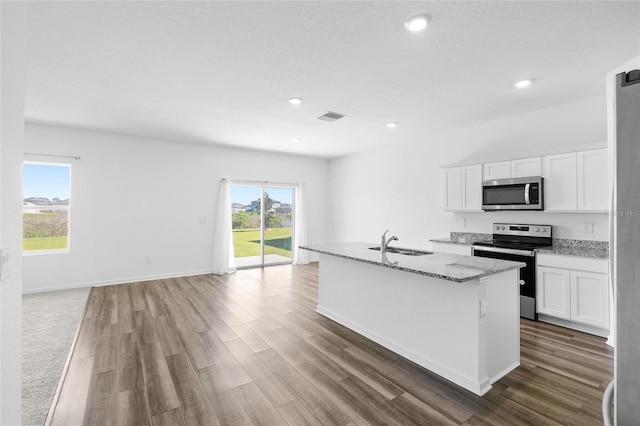 kitchen with visible vents, an island with sink, wood finished floors, stainless steel appliances, and a sink