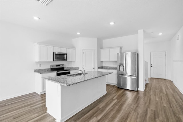 kitchen featuring a center island with sink, wood finished floors, white cabinets, stainless steel appliances, and a sink