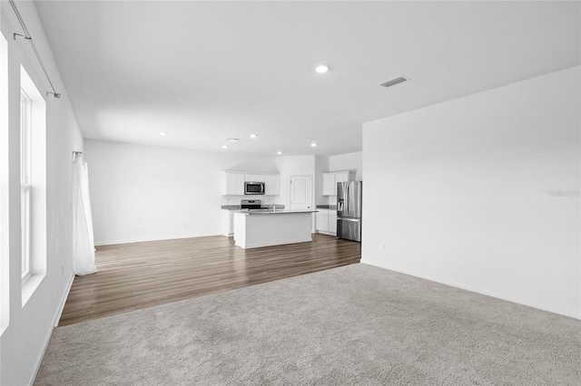 unfurnished living room with recessed lighting, carpet, visible vents, and baseboards