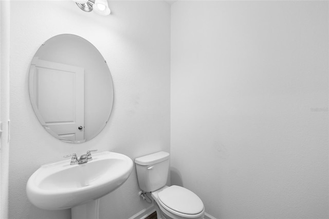 bathroom featuring a sink, baseboards, and toilet