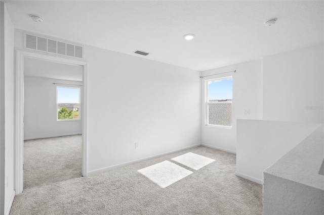 carpeted spare room featuring visible vents and baseboards