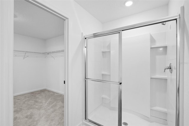 full bath featuring a walk in closet, baseboards, and a stall shower