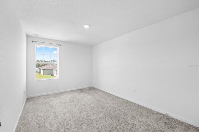 unfurnished room with carpet flooring and baseboards