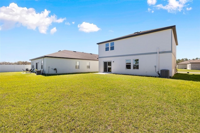 rear view of house with cooling unit, fence, and a yard