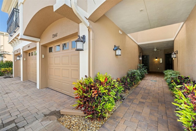 view of exterior entry with stucco siding, driveway, and an attached garage