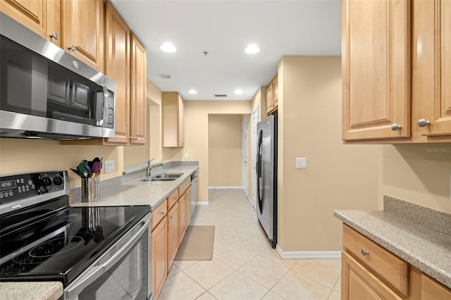 kitchen with a sink, recessed lighting, appliances with stainless steel finishes, light tile patterned floors, and baseboards