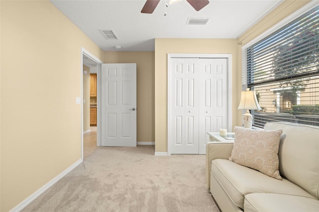 living area featuring visible vents, baseboards, light colored carpet, and a ceiling fan