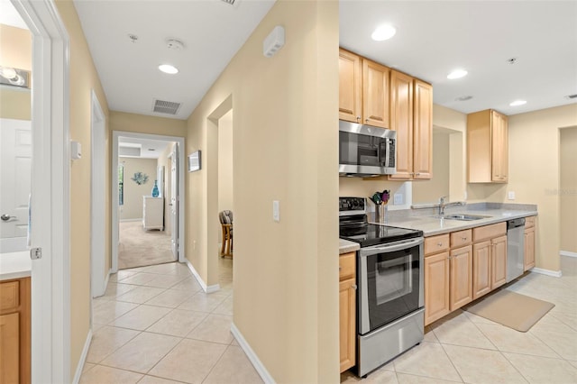 kitchen with a sink, stainless steel appliances, light brown cabinets, and light tile patterned floors