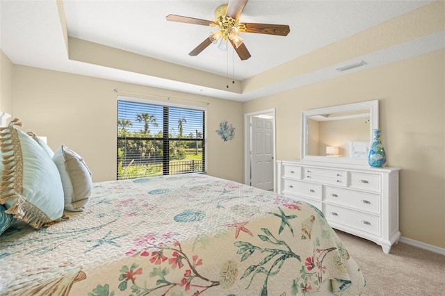 bedroom with visible vents, light carpet, a tray ceiling, baseboards, and ceiling fan