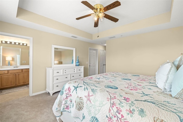 bedroom featuring a tray ceiling, light colored carpet, visible vents, and a sink