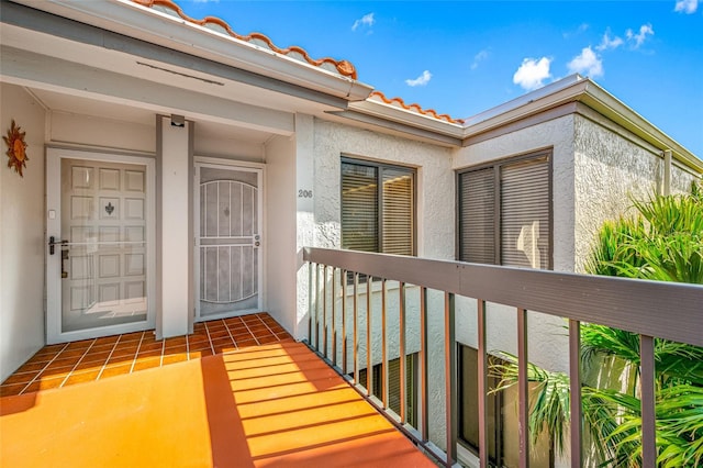 property entrance featuring stucco siding, a balcony, and a tile roof