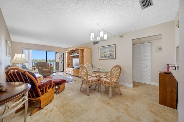 dining room featuring a notable chandelier, a textured ceiling, baseboards, and visible vents