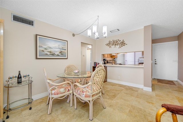 dining space featuring visible vents, a textured ceiling, and an inviting chandelier