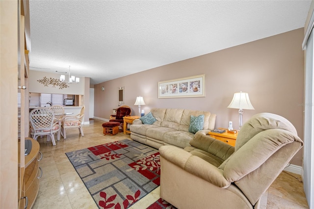 living area with baseboards, tile patterned floors, a textured ceiling, and an inviting chandelier