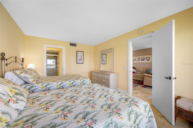 bedroom with visible vents, light colored carpet, a textured ceiling, and connected bathroom