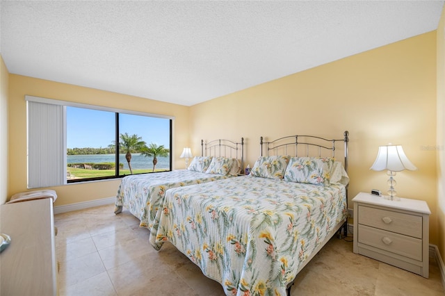 tiled bedroom with baseboards and a textured ceiling