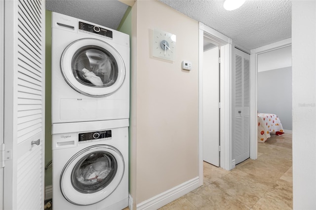 laundry room featuring baseboards, stacked washer and dryer, and a textured ceiling