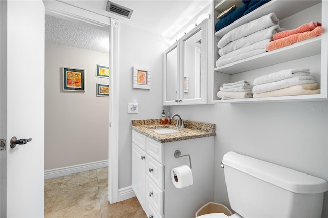 half bathroom featuring vanity, baseboards, visible vents, a textured ceiling, and toilet